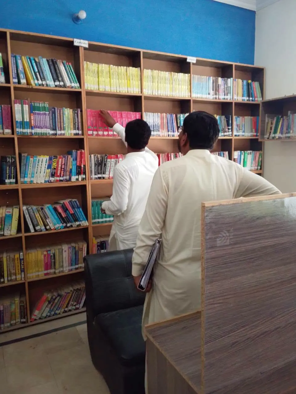 A student and a librarian selecting books from the library shelves